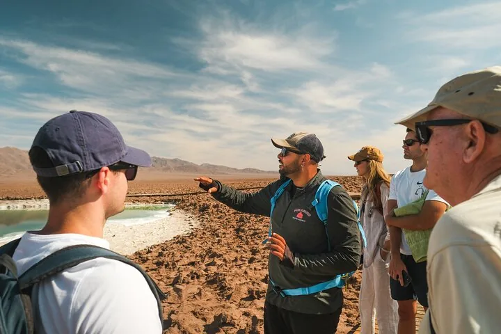 Tour group standing on a wooden boardwalk near a salt lake.